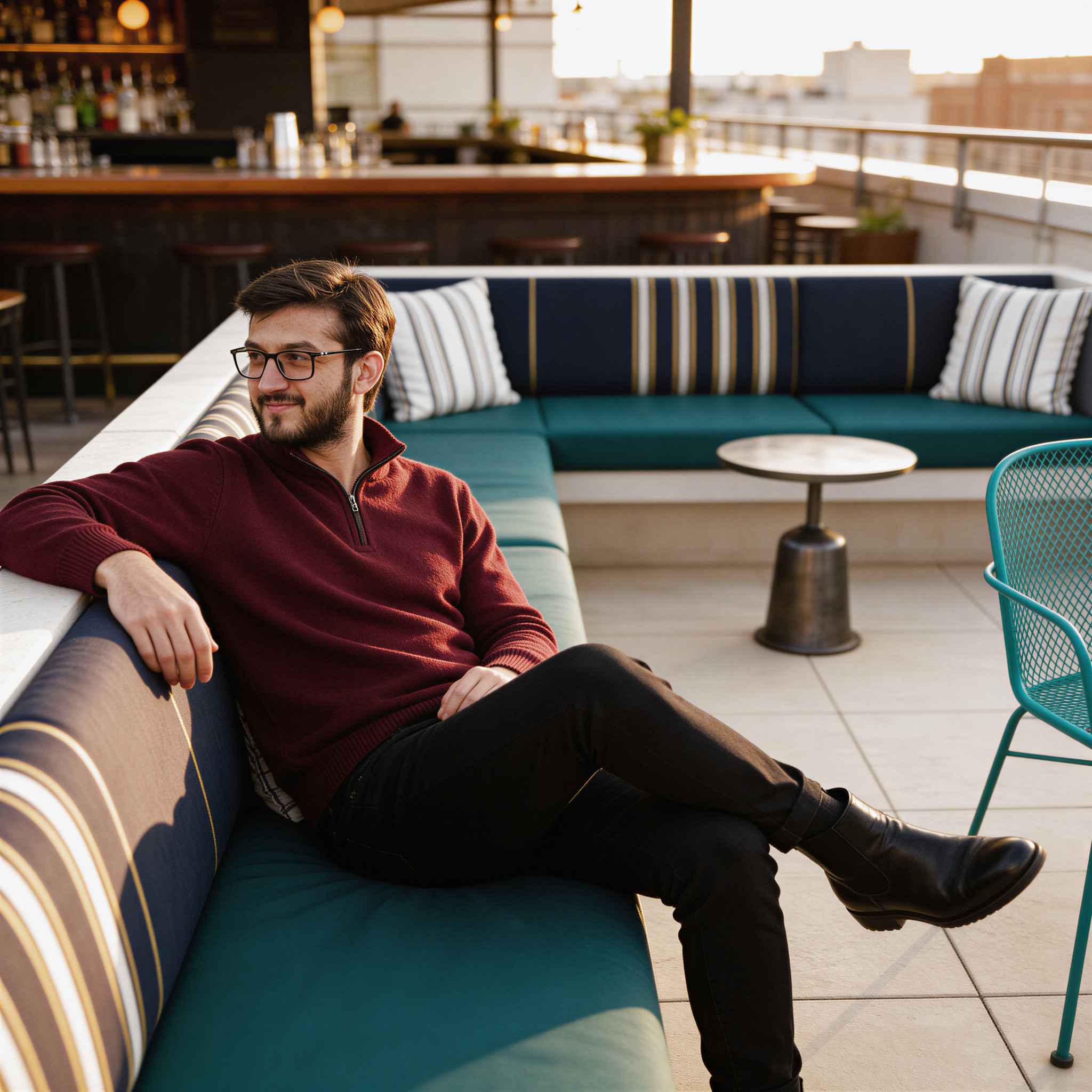 Man in a maroon quarter-zip relaxing at a rooftop bar at golden hour, an example of a strong Hinge profile photo
